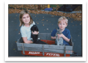Cropped photo of two children sitting in a red wagon, straightened and extracted from the scan